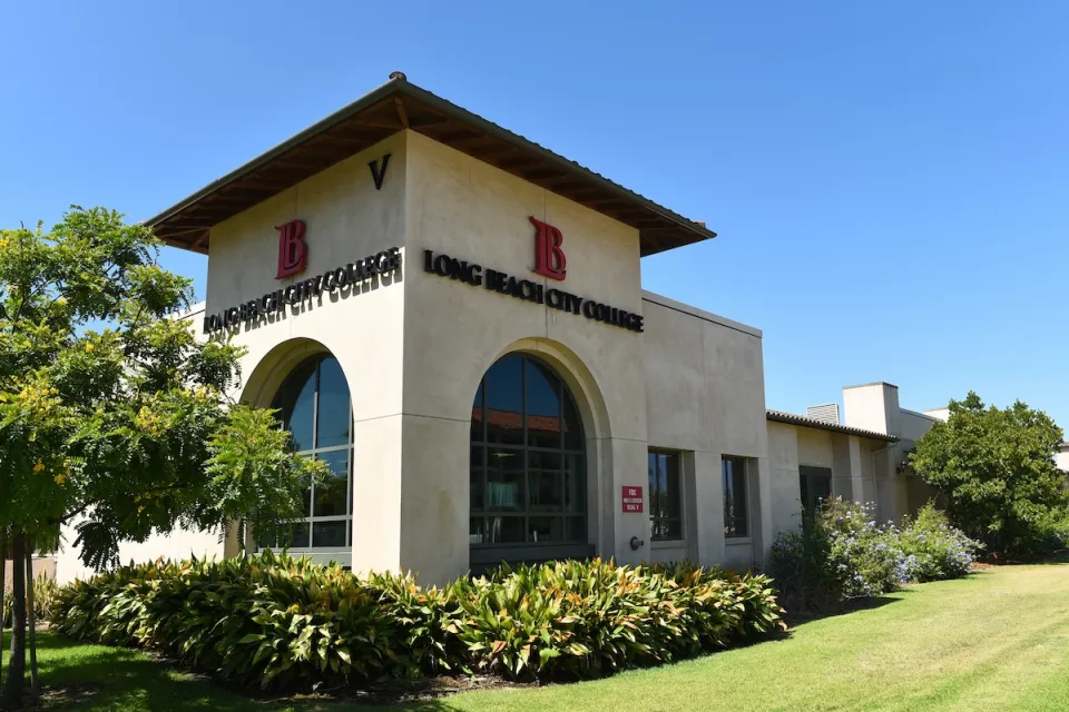 Corner view of Spanish revival-style building with arched windows, red tile roof, and Long Beach City College title and logo on two sides.